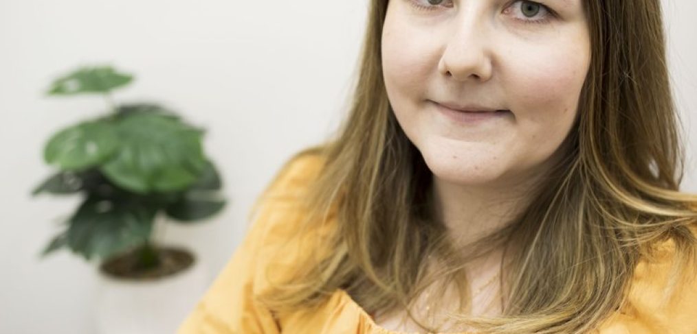 a woman wearing yellow blouse, smiling and looking into the camera