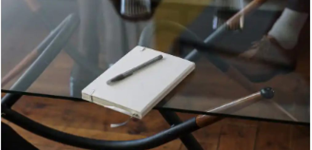 notebook and a pen placed on top of a clear glass table