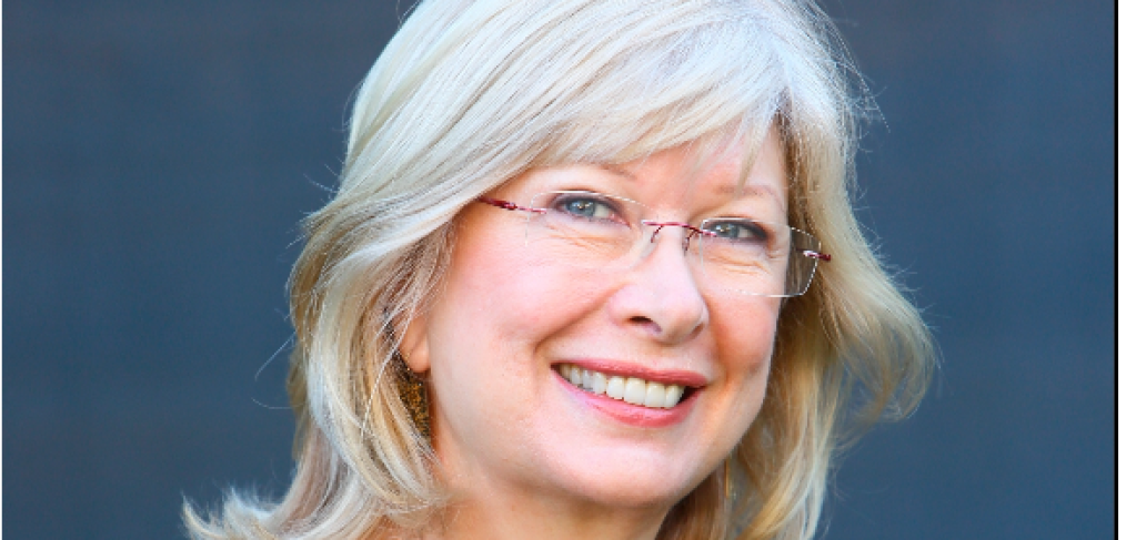Carolyn Rogers - Woman with short blonde hair and wearing glasses and blue top, smiling