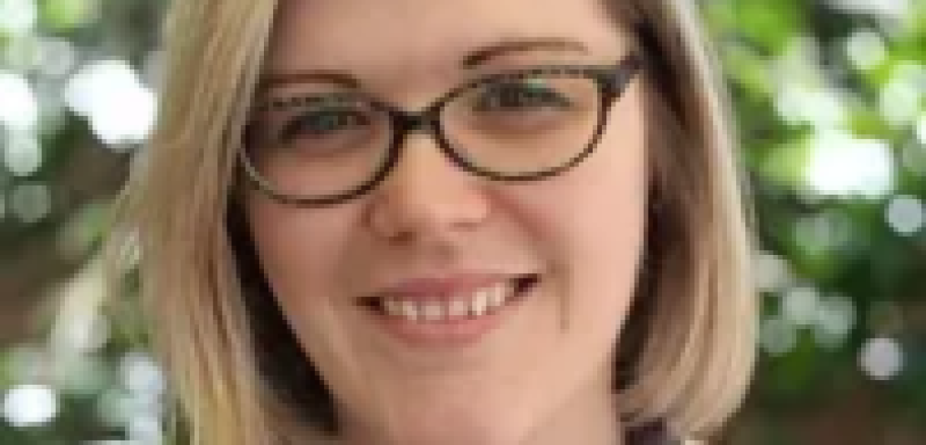 Photo of Erin Hitzke. Woman with blonde hair, wearing glasses smiling